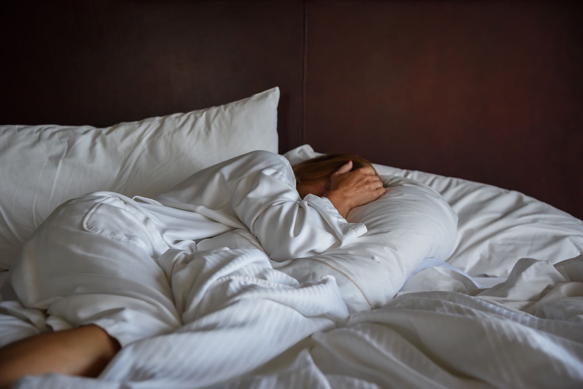 Woman laying in bed covering head